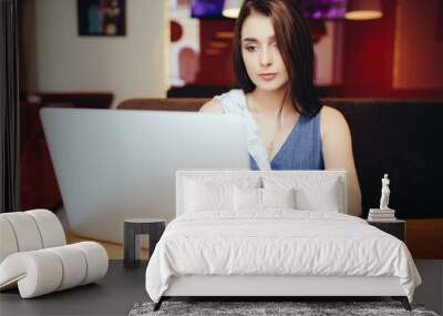 Casual woman using laptop at coffee shop Wall mural